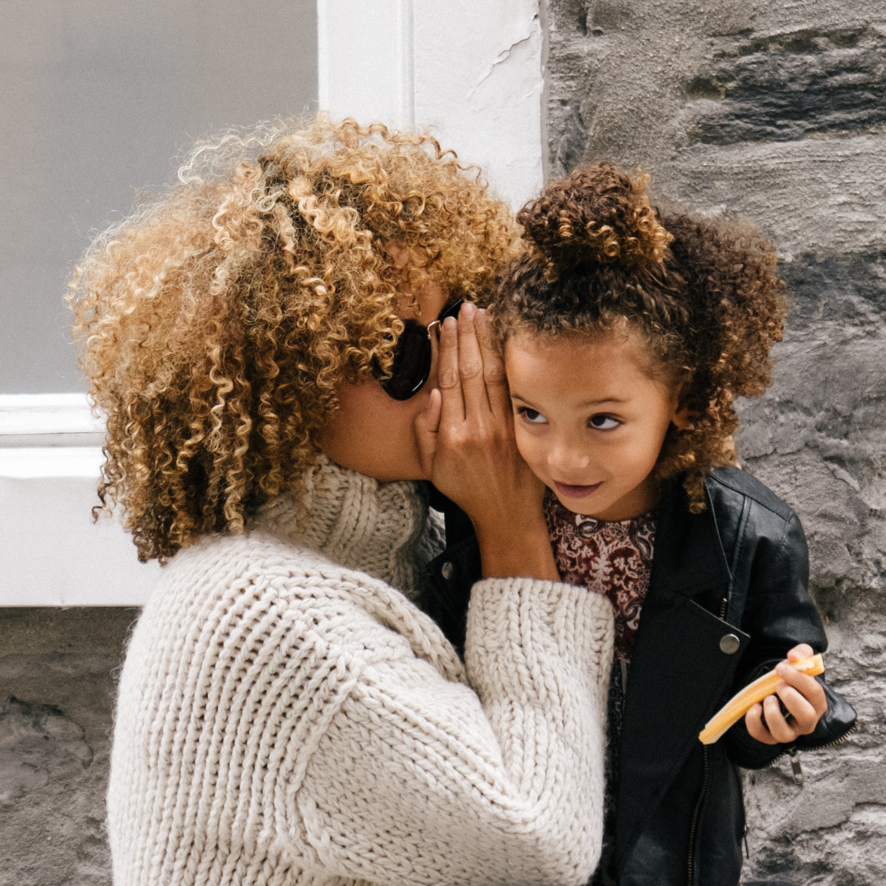 Mother whispering to her daughter.