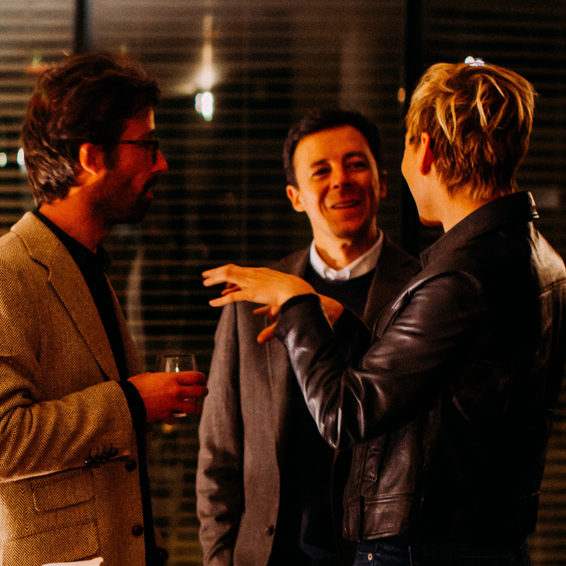 Three individuals talking in a dimly lit room.