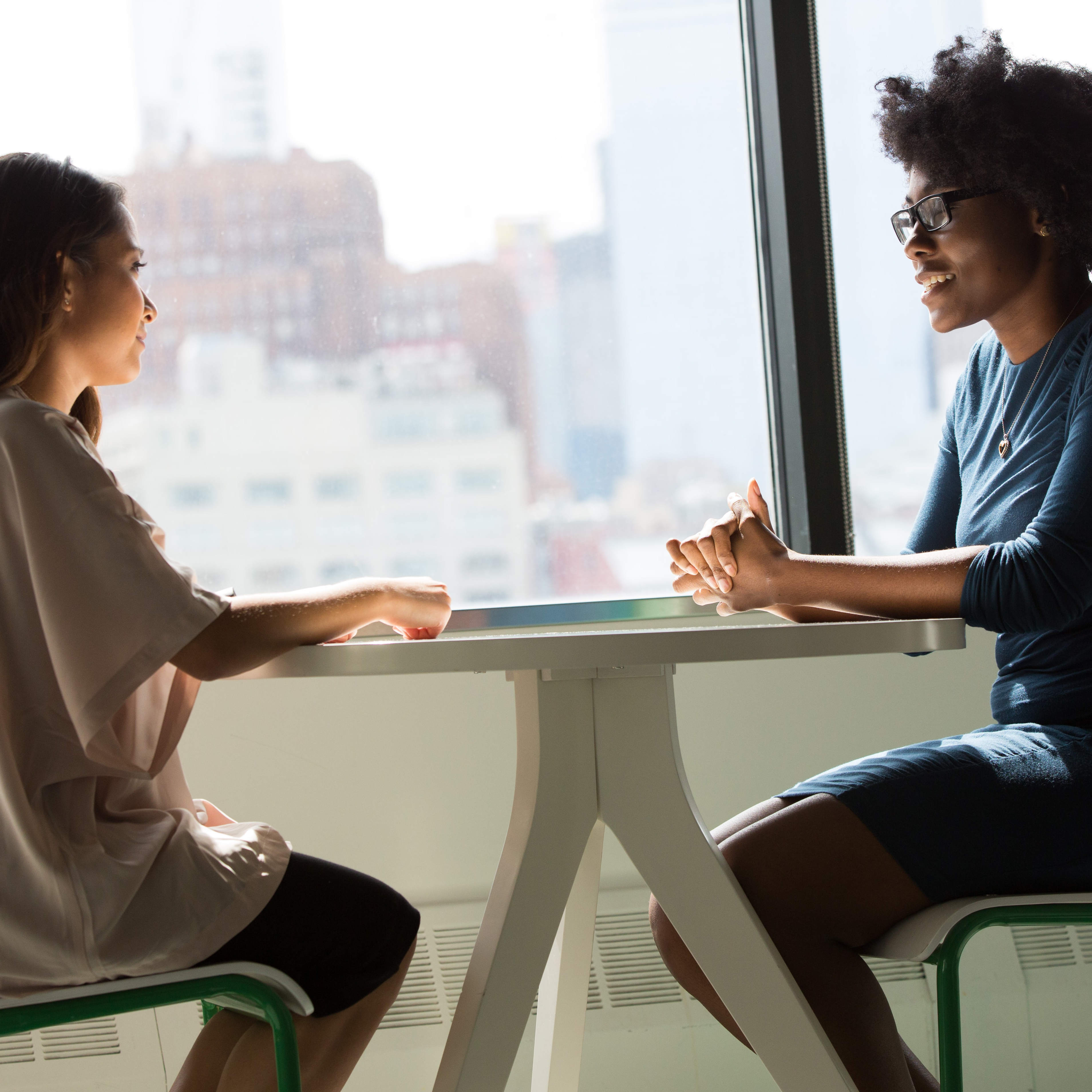 Two individuals talking at a table. Photo by Photo by Christina @ wocintechchat.com