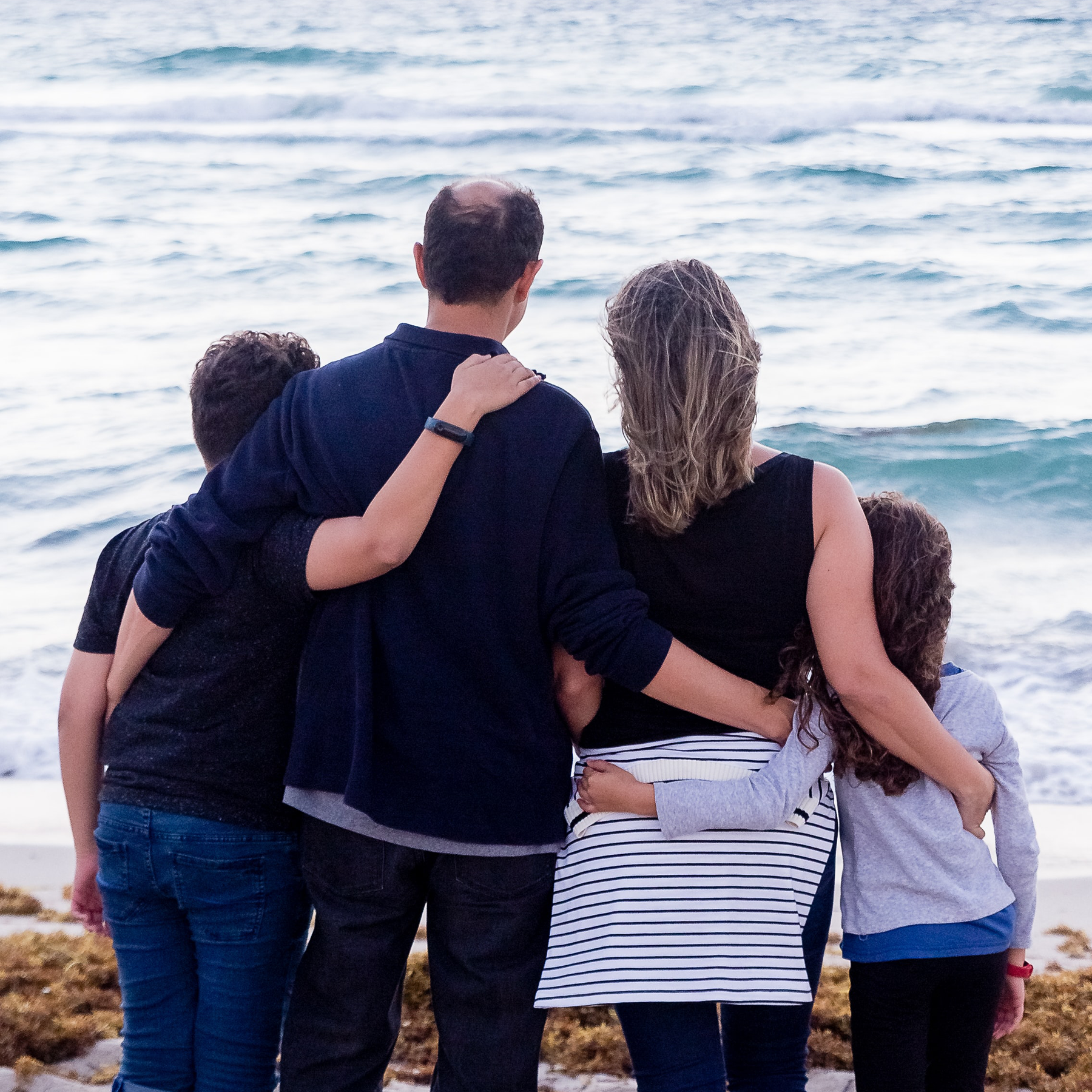 Family of four hugging each other.